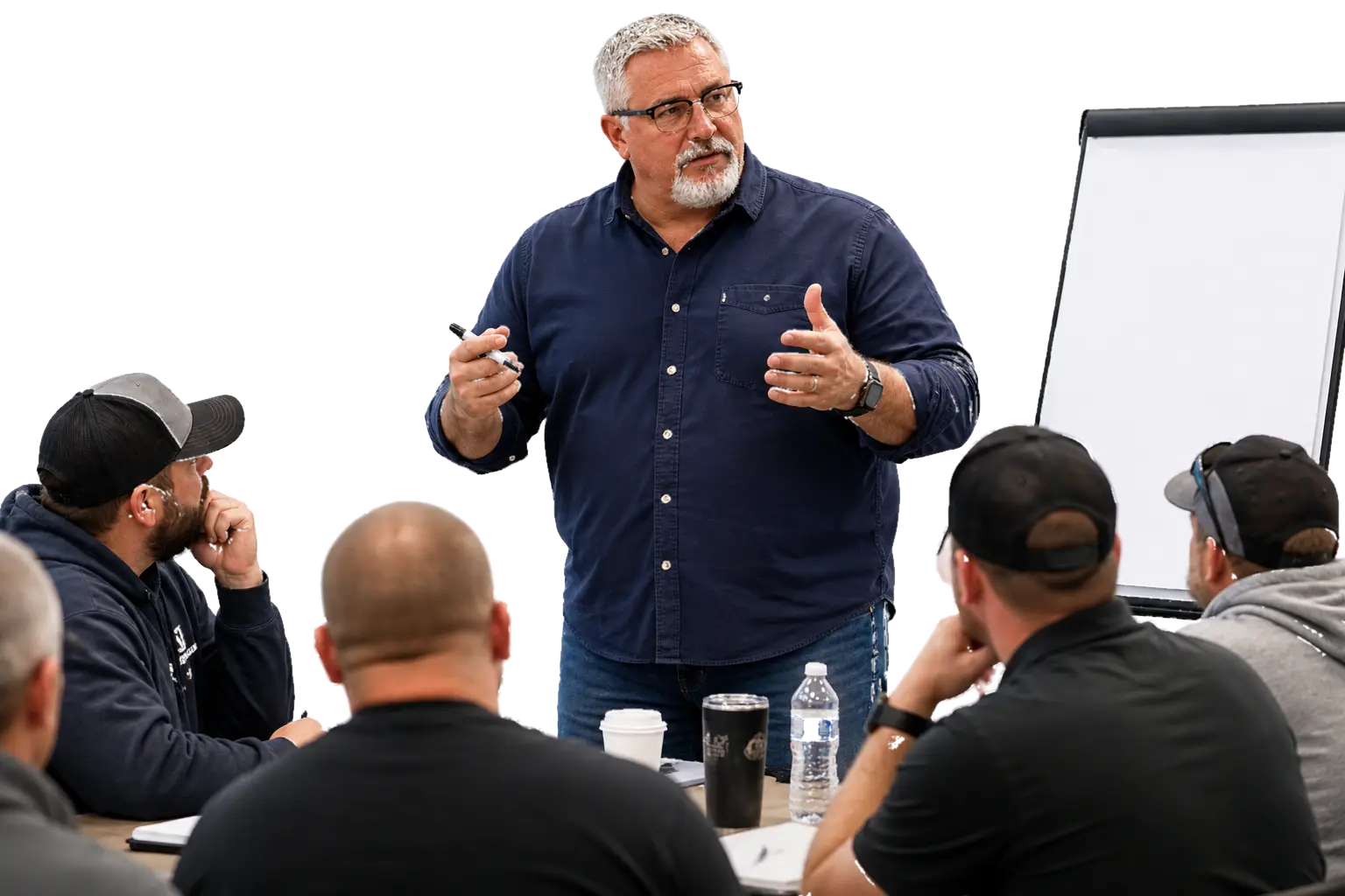 Jon Robertson standing at a whiteboard leading a training session for a room of contractors seated around a table